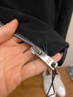 Prada jacket zipper pull with metal slider and dark fabric tape, close-up