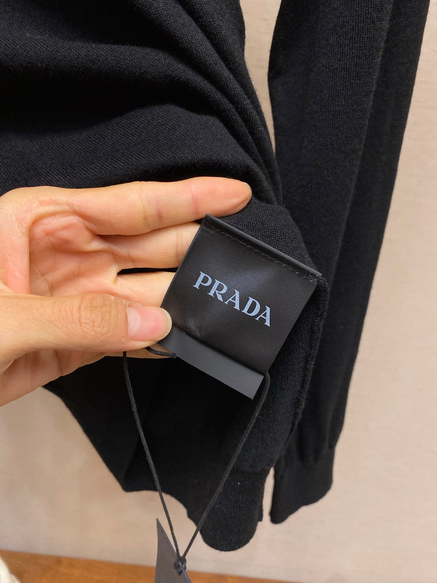 Prada fabric tag attached to dark knit sweater
