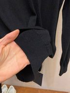 Sweater hem and cuff detail in dark knit, held in hand