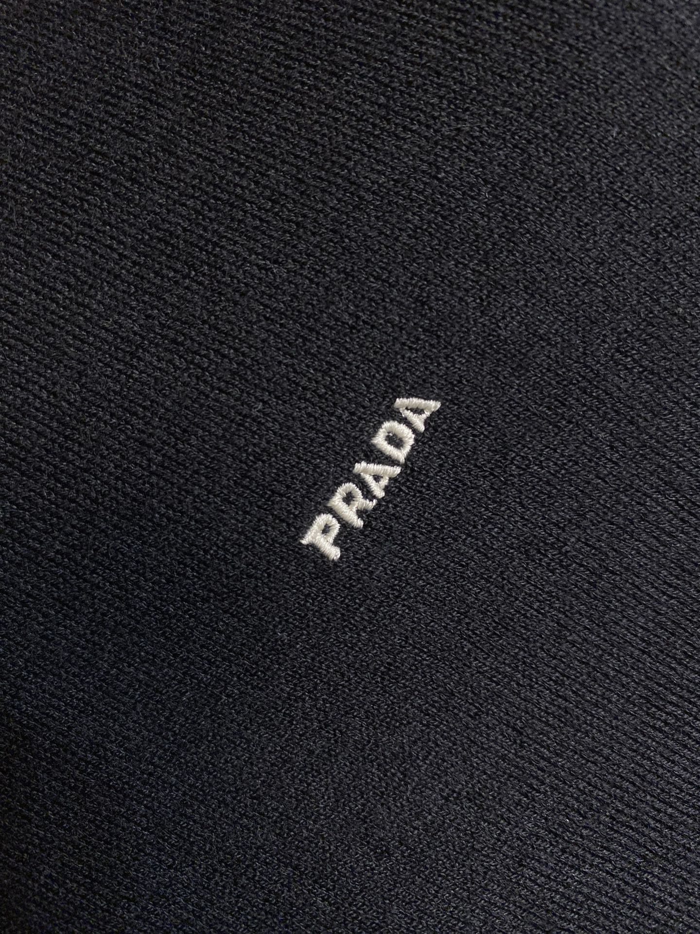 Dark knit sweater fabric with small PRADA logo stitch