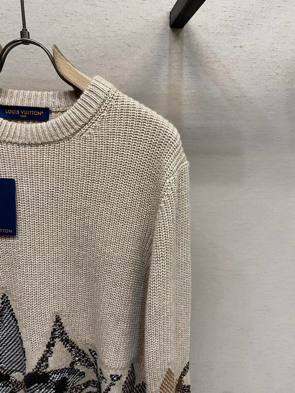 Cream knit sweater with ribbed crew neck and long sleeve, dark jacquard hem motif