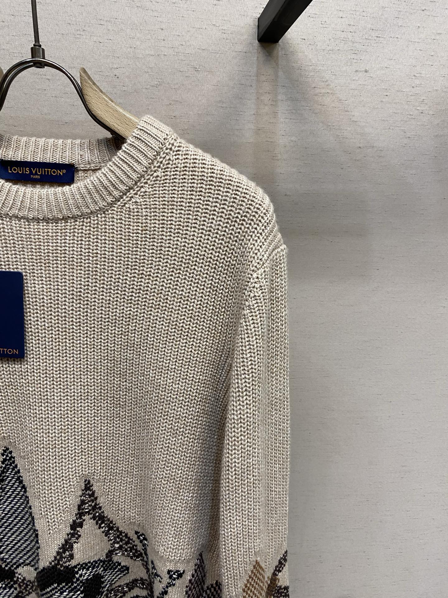 Cream knit sweater with ribbed crew neck and long sleeve, dark jacquard hem motif