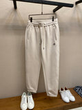 Cream Moncler track pants with elastic waistband and drawstring, front patch pocket