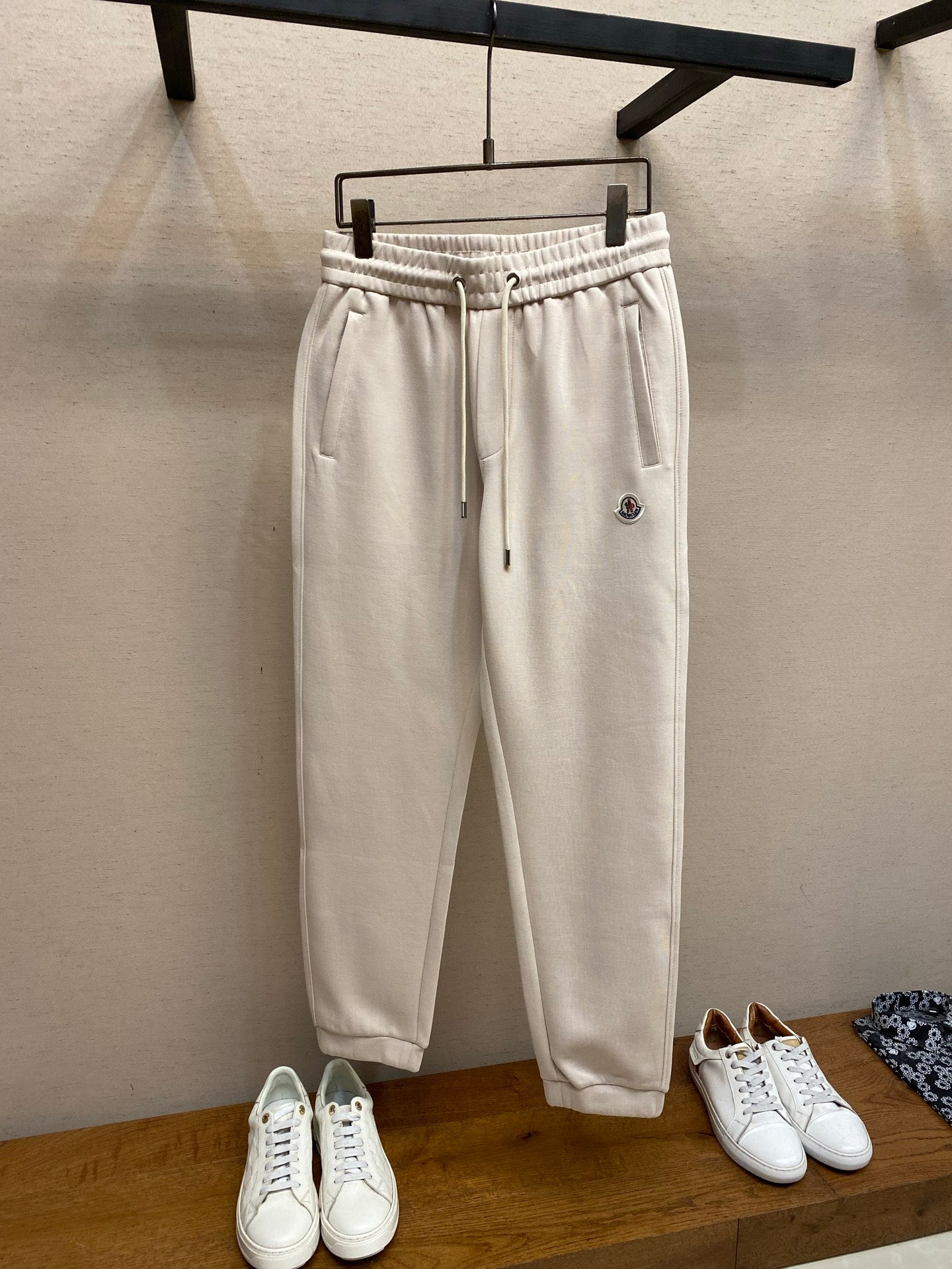 Cream Moncler track pants with elastic waistband and drawstring, front patch pocket