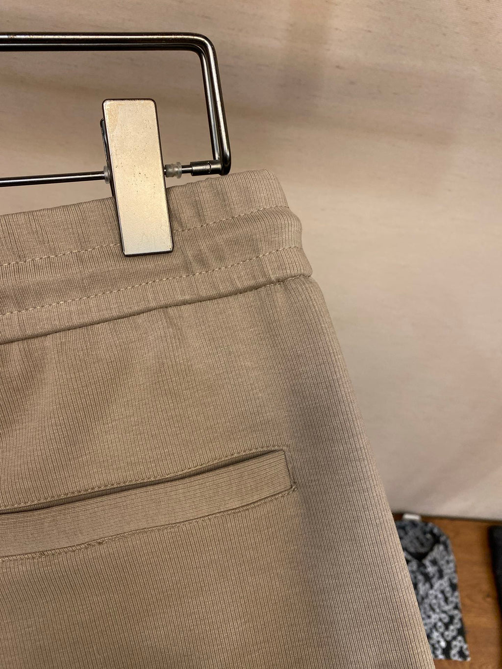 Beige sweatpants waistband detail with metal button and inner pocket