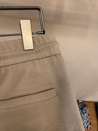 Beige sweatpants waistband detail with metal button and inner pocket