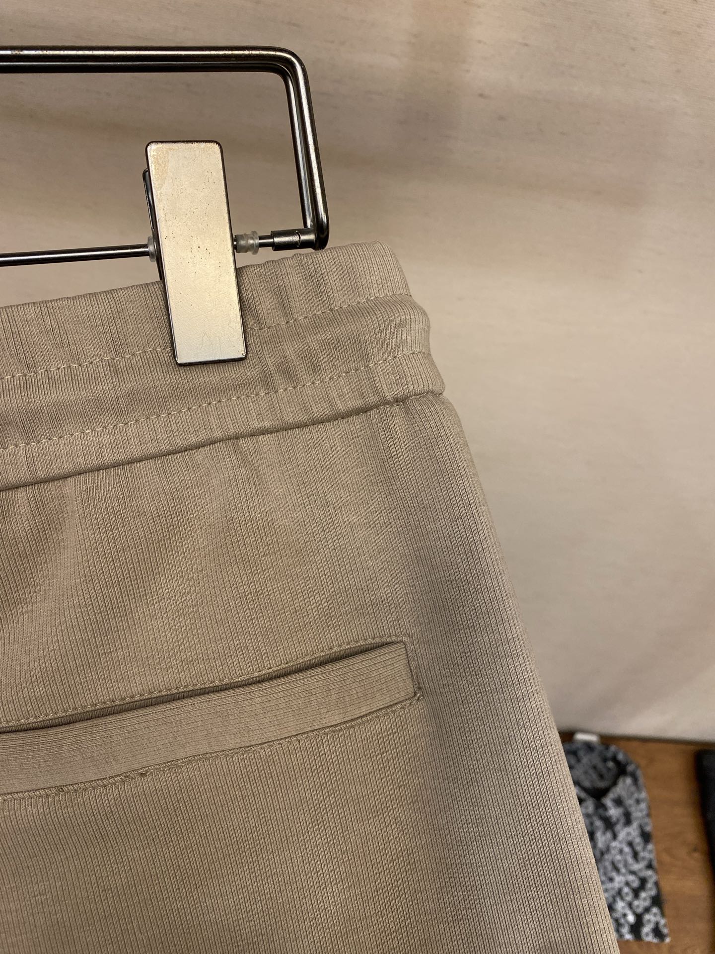 Beige sweatpants waistband detail with metal button and inner pocket