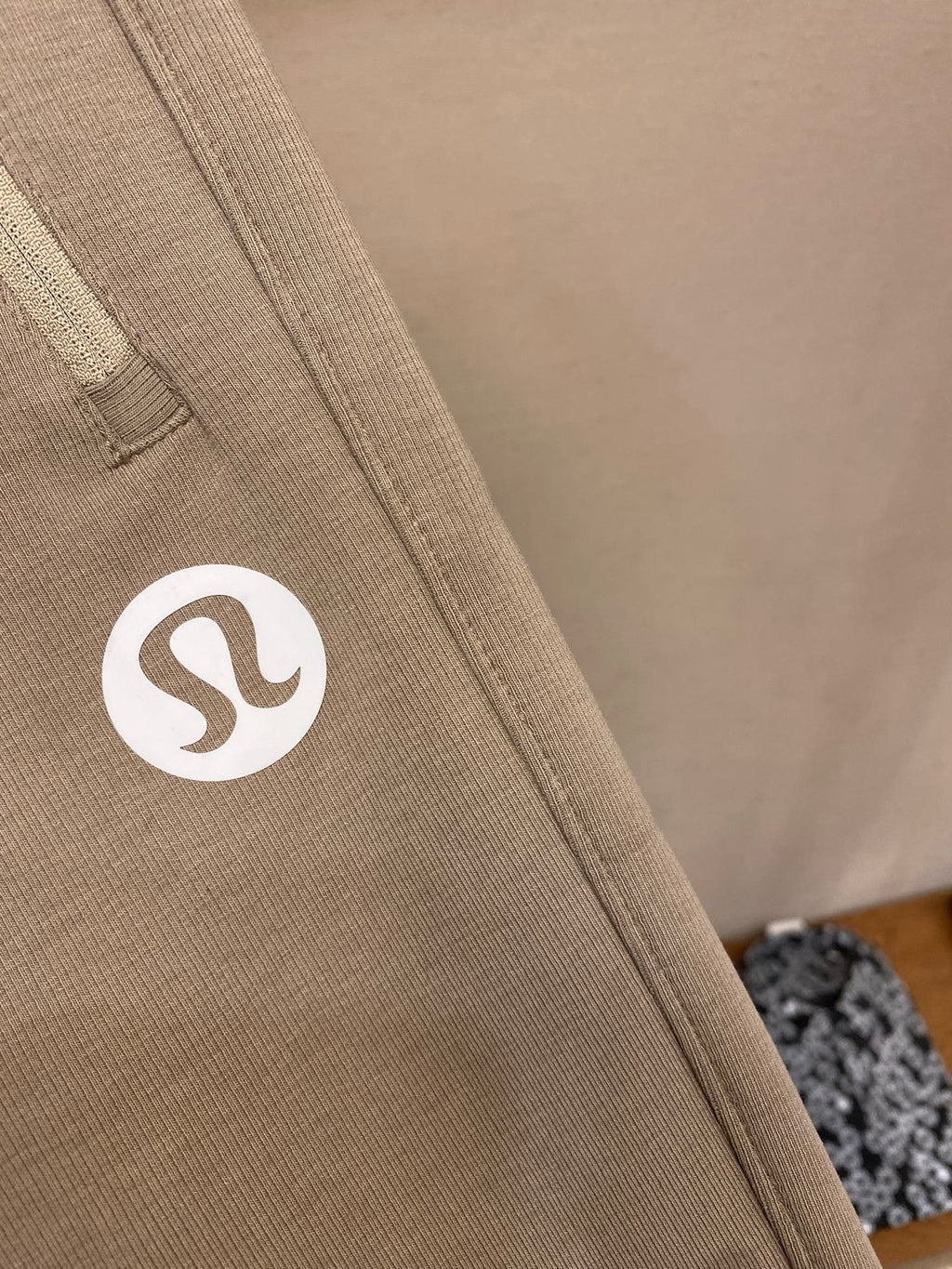 Beige sweatpants fabric with circular logo patch on side
