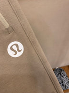 Beige sweatpants fabric with circular logo patch on side