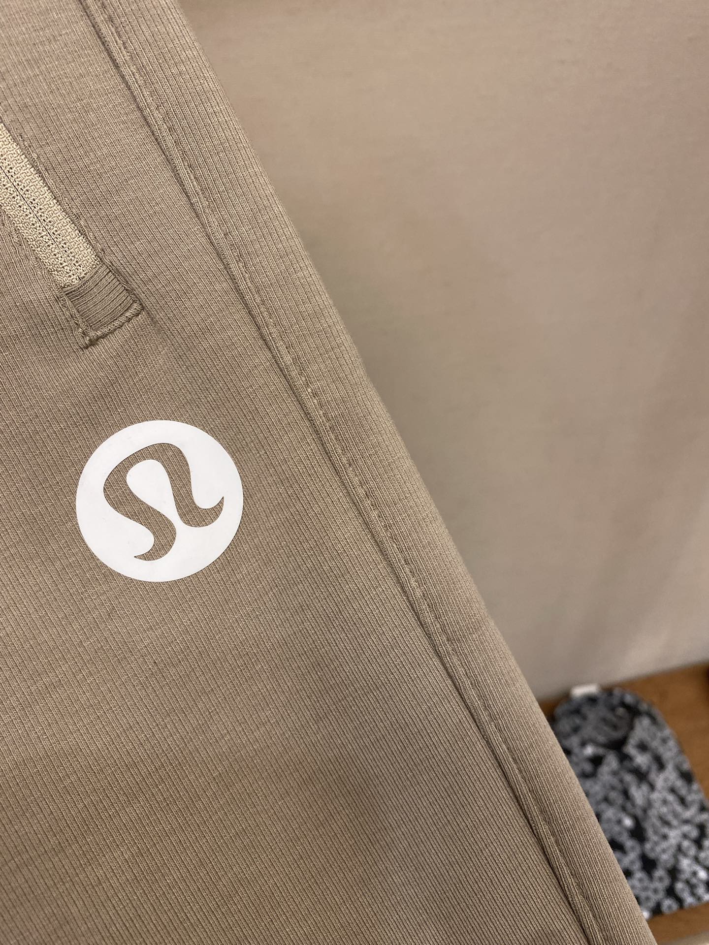 Beige sweatpants fabric with circular logo patch on side