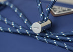 Prada-branded round zipper pull on dark-blue nylon trim with blue cords