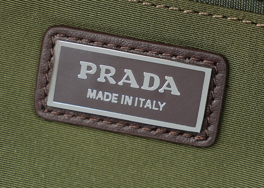 Prada Made in Italy label on green fabric with brown stitched leather border.