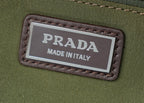 Prada Made in Italy label on green fabric with brown stitched leather border.