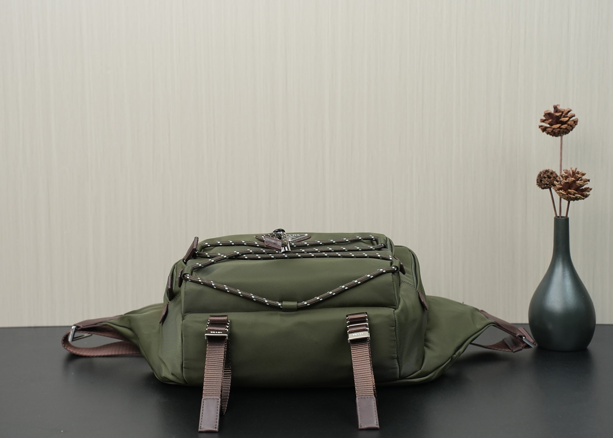 Green Prada bag front-top view with quilted logo panel and two front strap buckles.