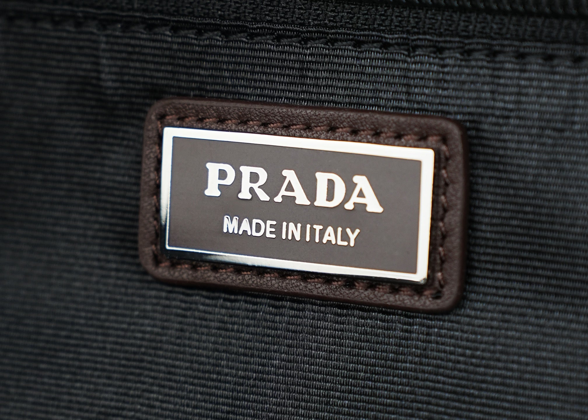Made in Italy label patch on black fabric belt bag.