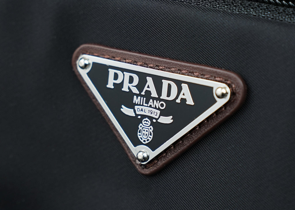 Triangular PRADA logo patch with PRADA MILANO text on brown leather trim.