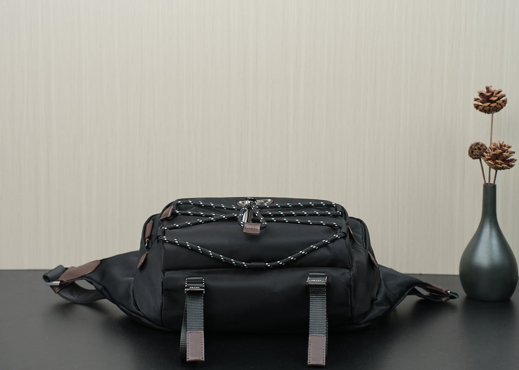 Black belt bag with braided top panel, leather tabs, and front strap loops.