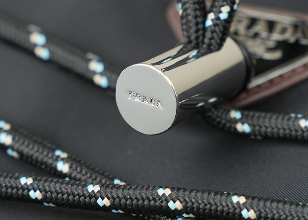 Braided cord with silver metal end cap labeled PRADA.