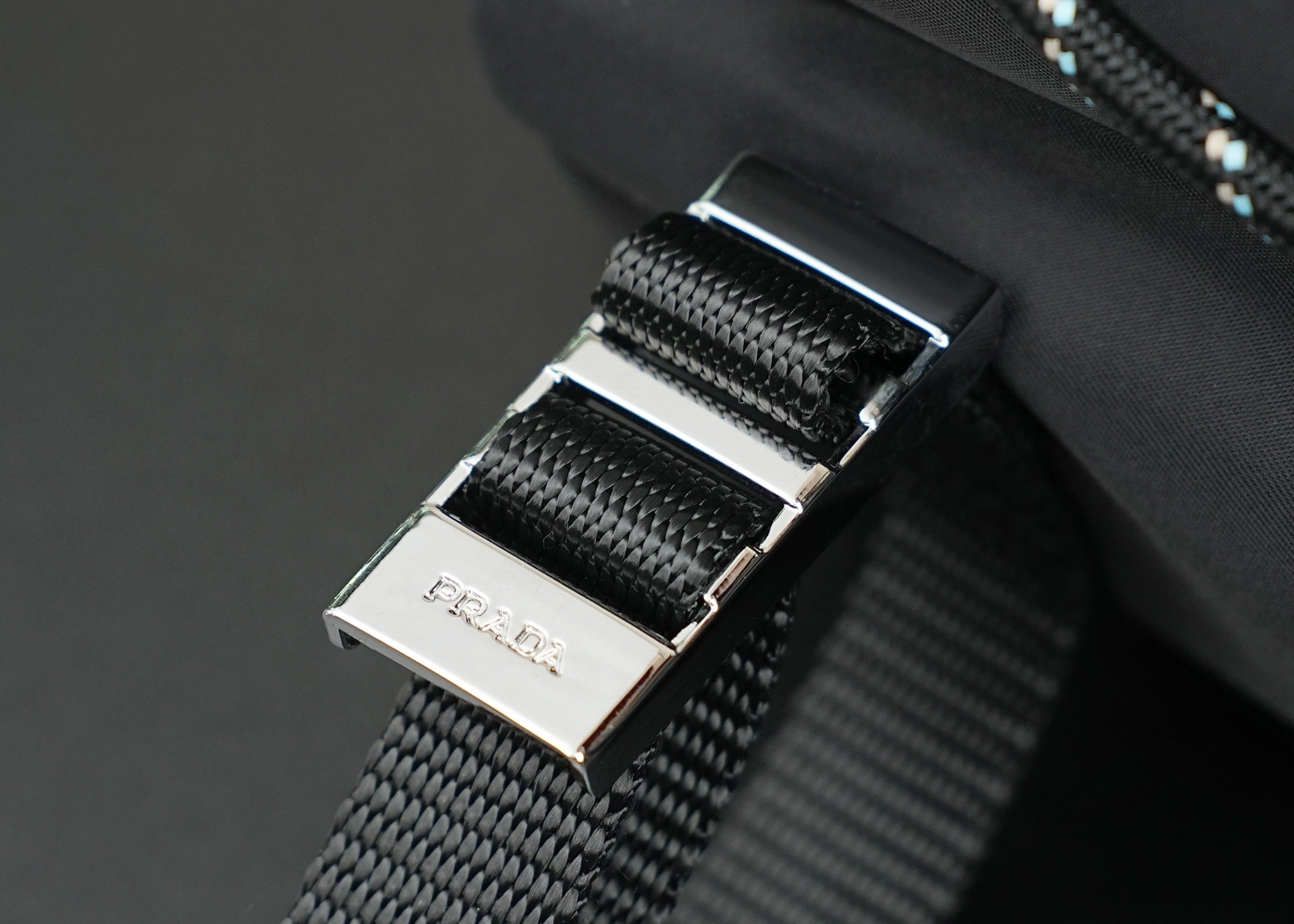 Metal buckle hardware on woven strap with brushed silver accents.