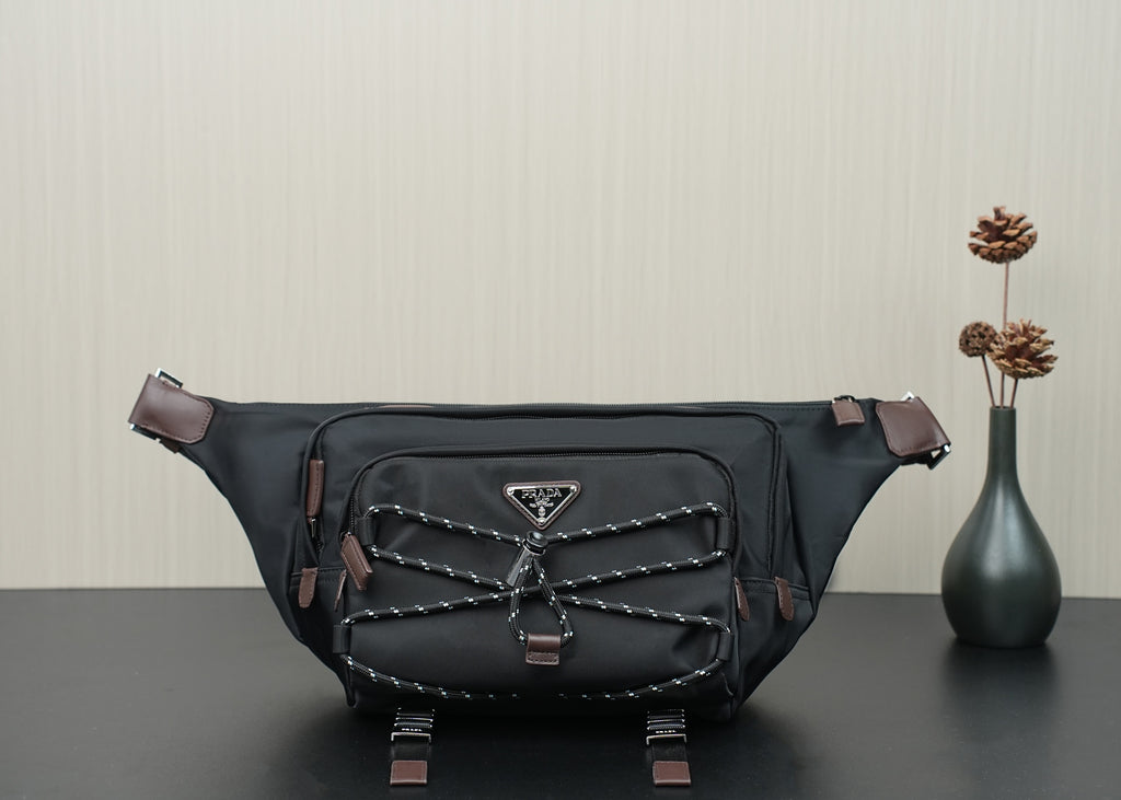 Prada belt bag in black with front logo plaque, braided trim, and adjustable straps.