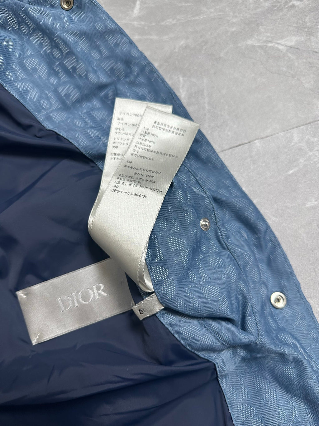 Blue long puffer vest with Dior label and folded price tag