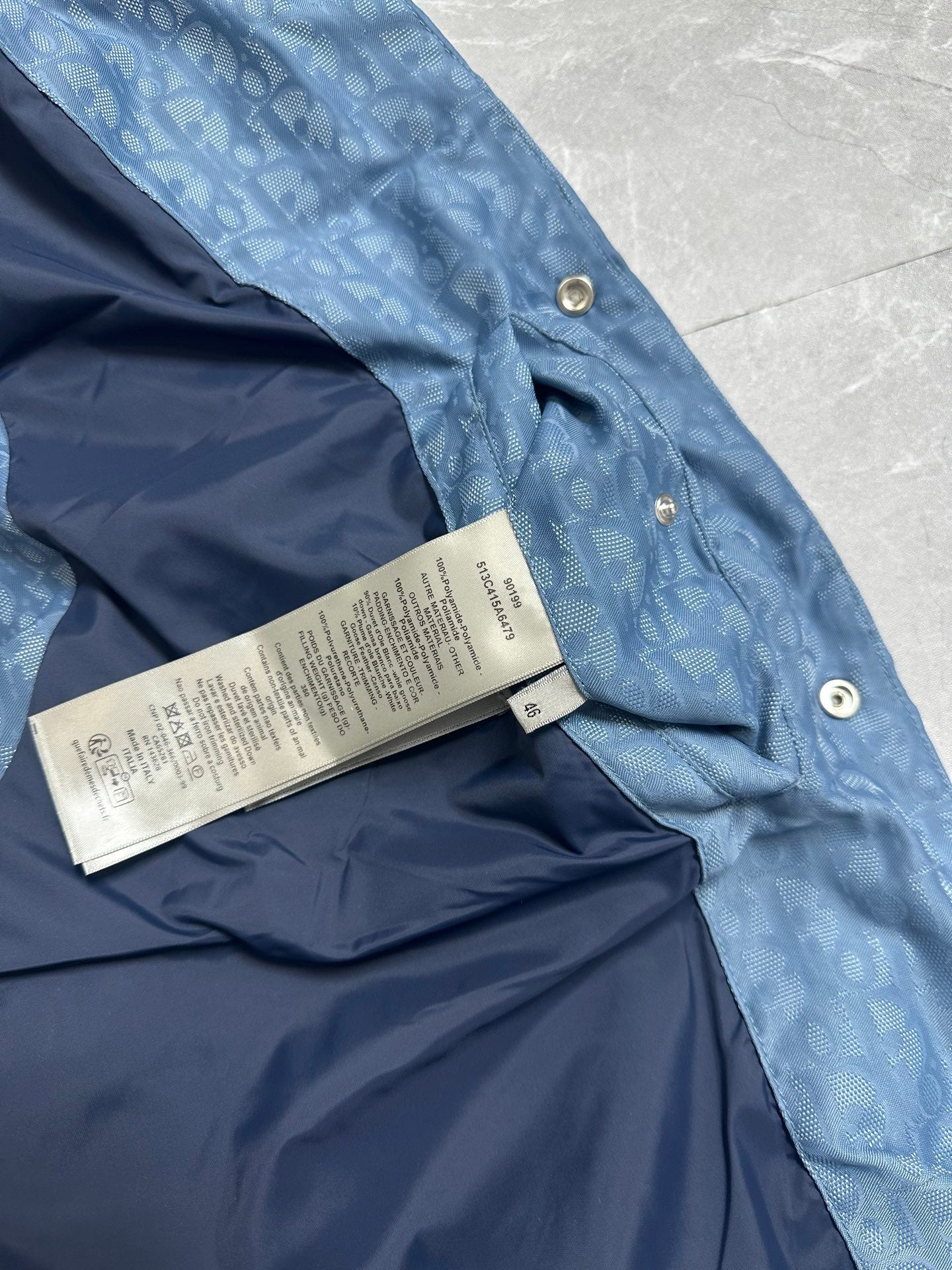 Blue puffer vest interior with printed size tag near snap buttons