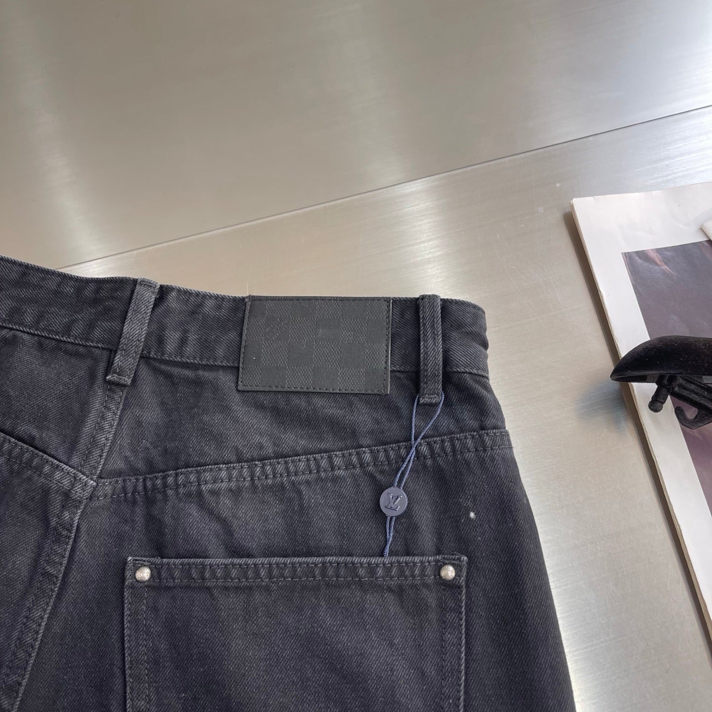 Dark denim pants waistband with button, belt loops, and hanging tag