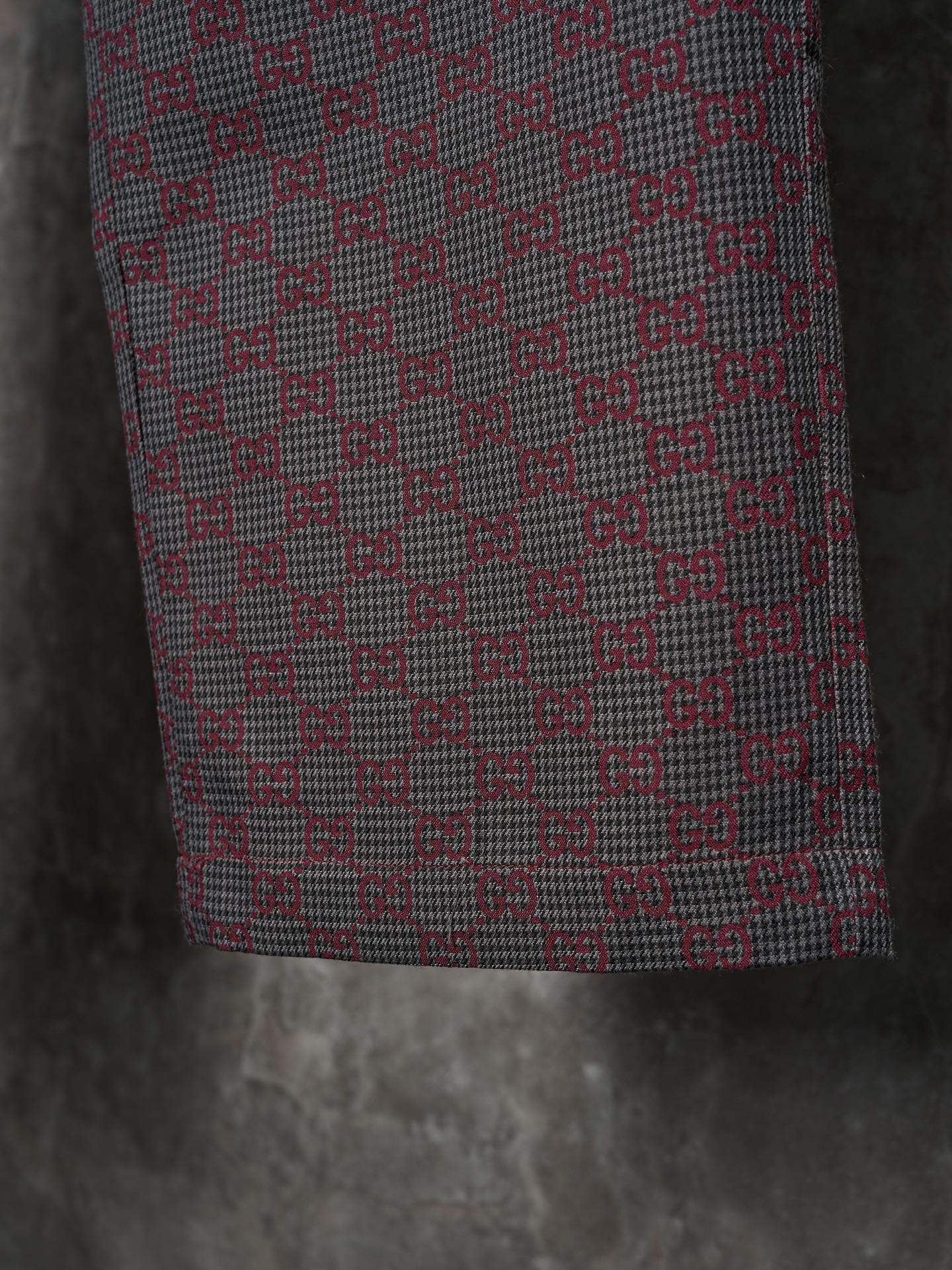 Gucci pants lower-leg close-up, maroon and gray GG-pattern woven fabric