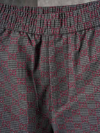 Gucci pants fabric close-up in maroon and gray GG lattice pattern with elastic waistband
