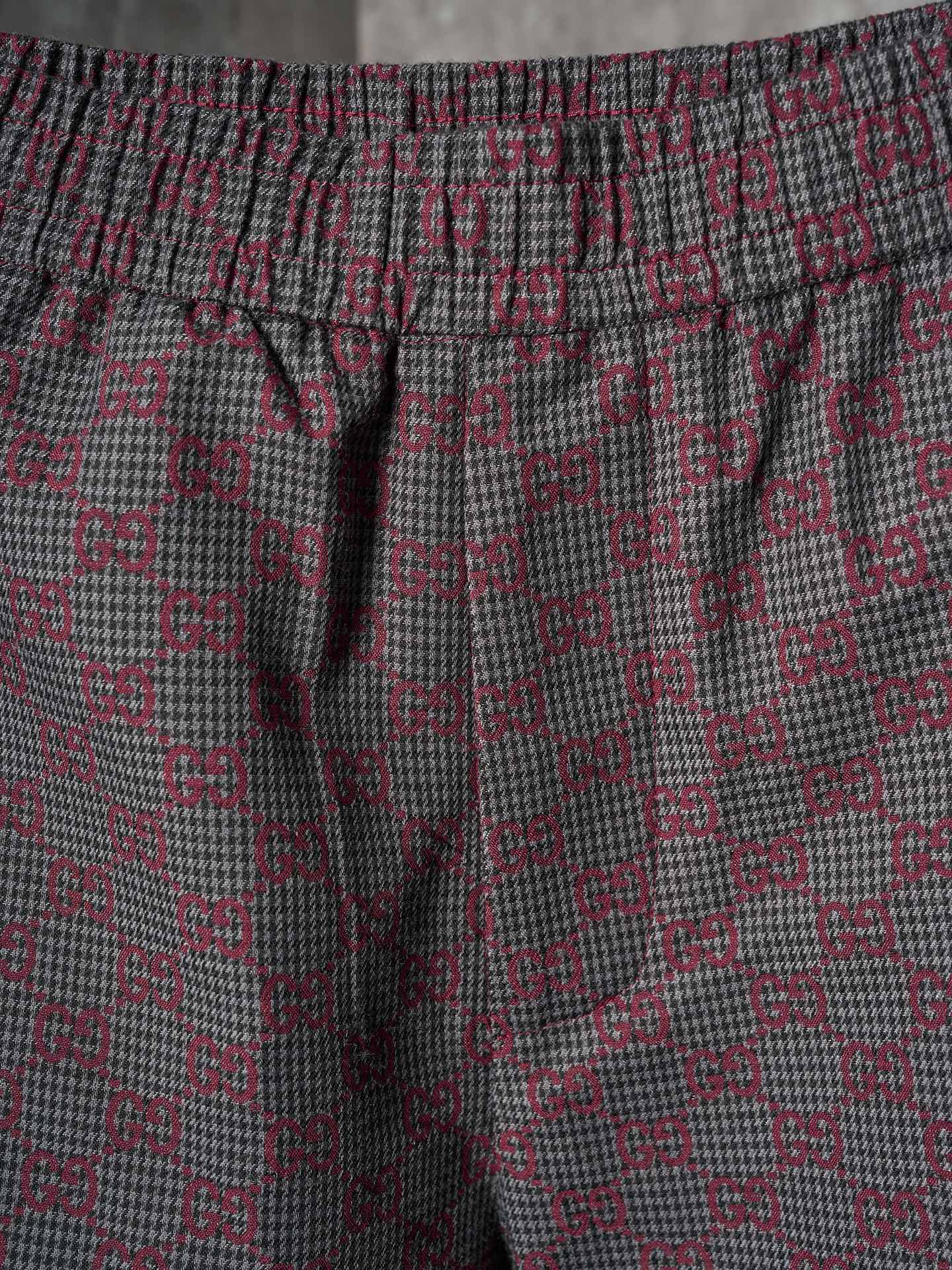 Gucci pants fabric close-up in maroon and gray GG lattice pattern with elastic waistband