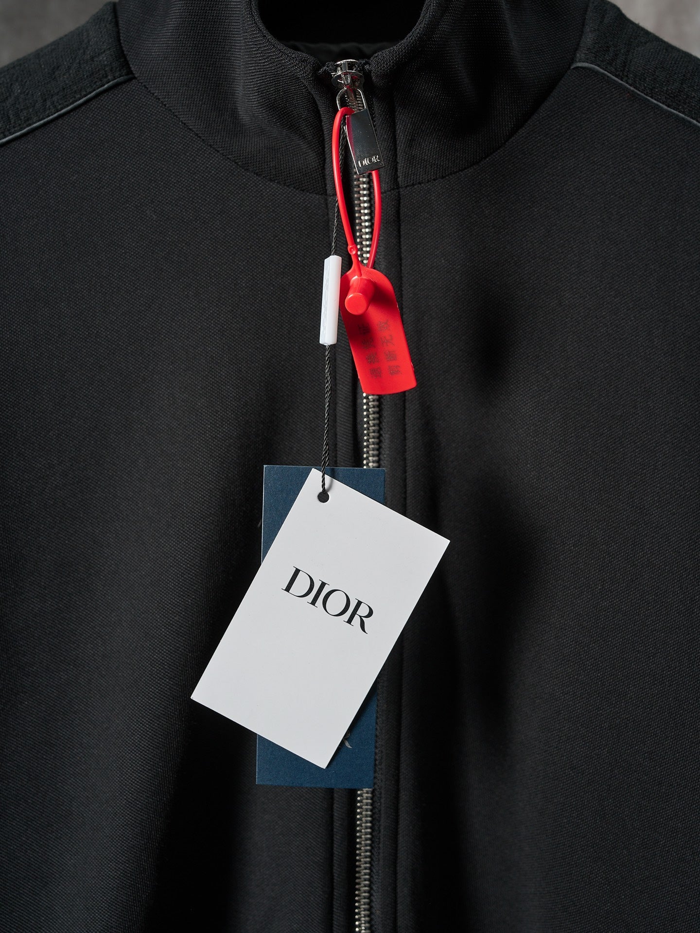 Black Dior zip-up jacket with red zipper pull and stand collar