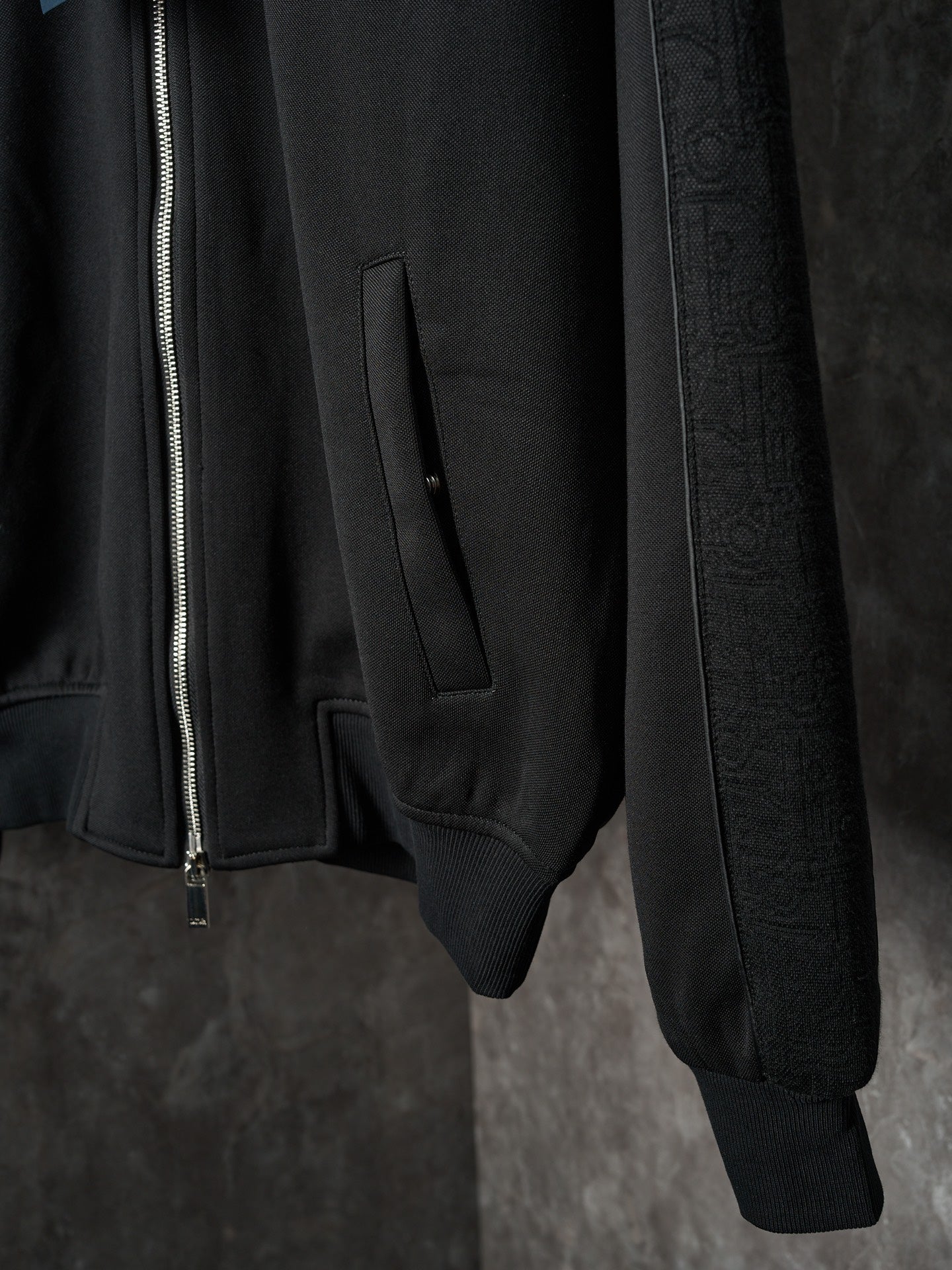 Black Dior zip-up jacket closeup of front pocket and ribbed cuffs