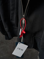 Black Dior zip-up jacket zipper closeup with red cord pull