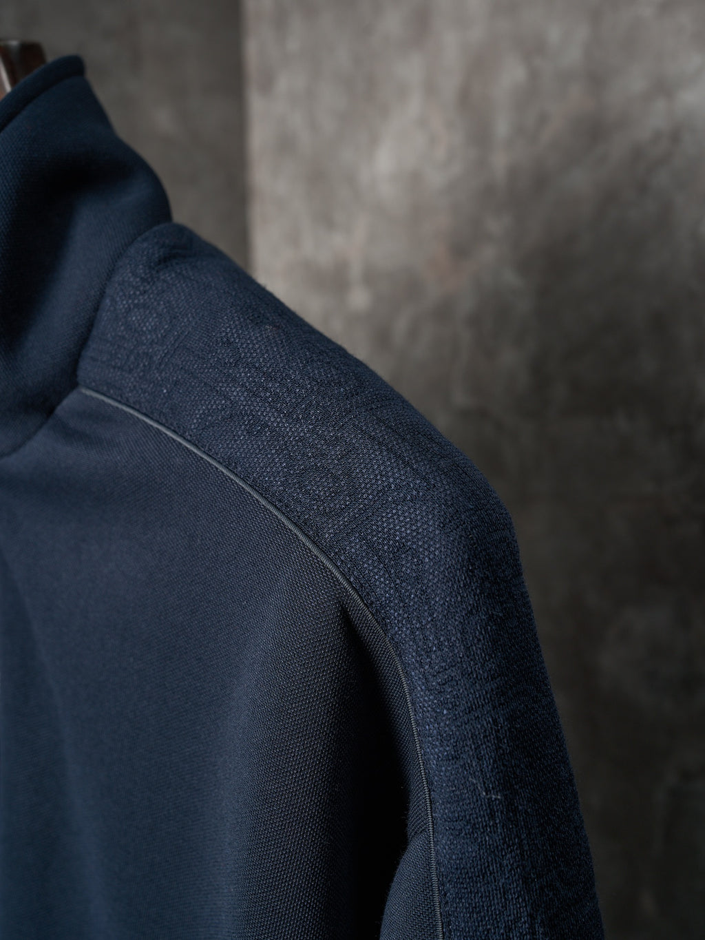 Navy jacket sleeve with textured fabric and stitched shoulder seam