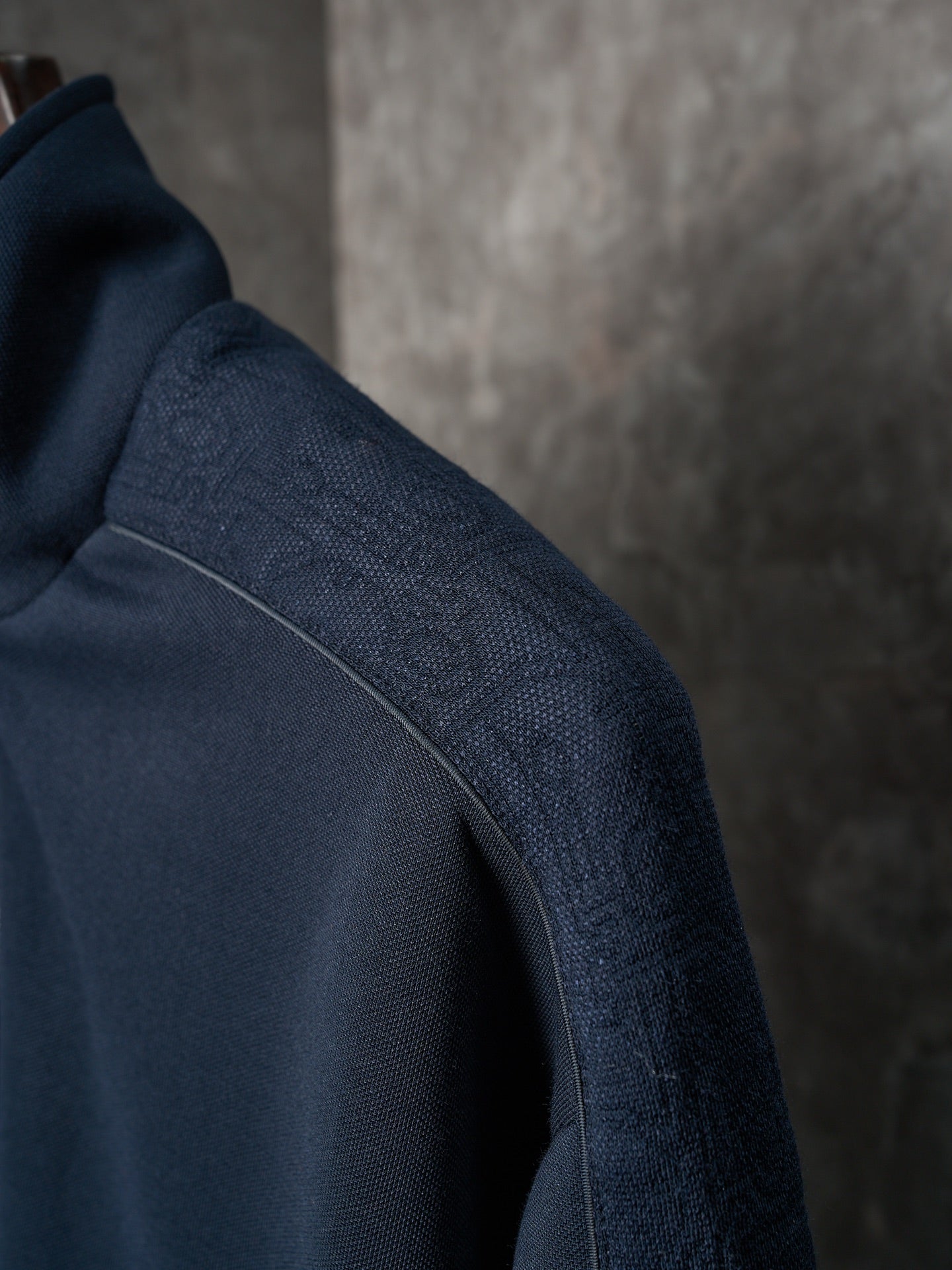 Navy jacket sleeve with textured fabric and stitched shoulder seam