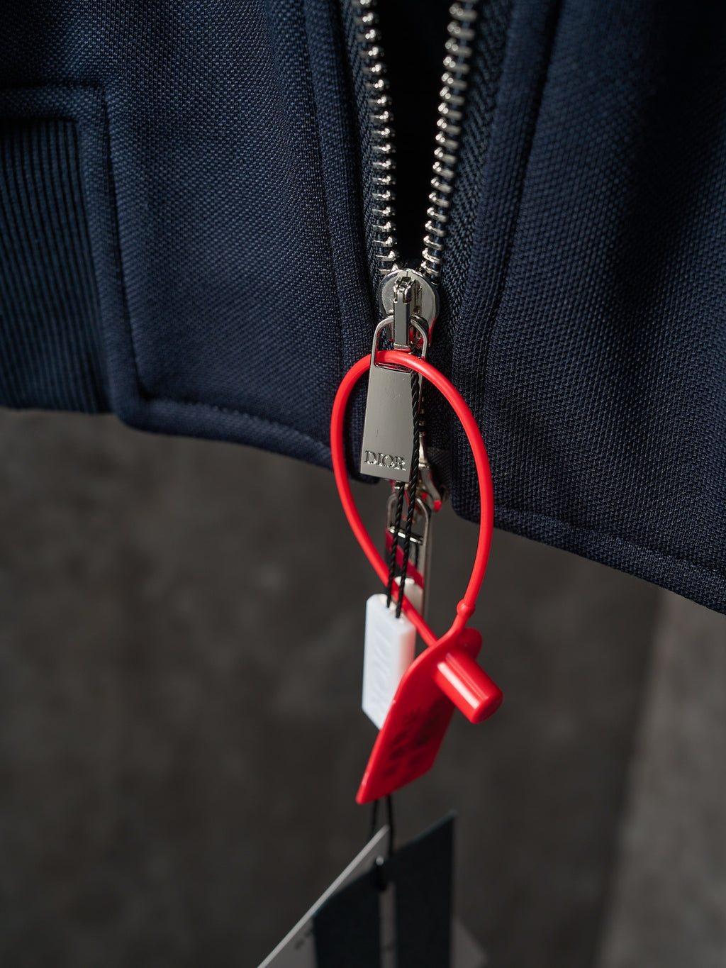 Navy jacket zipper with metal pull and red keyring tag