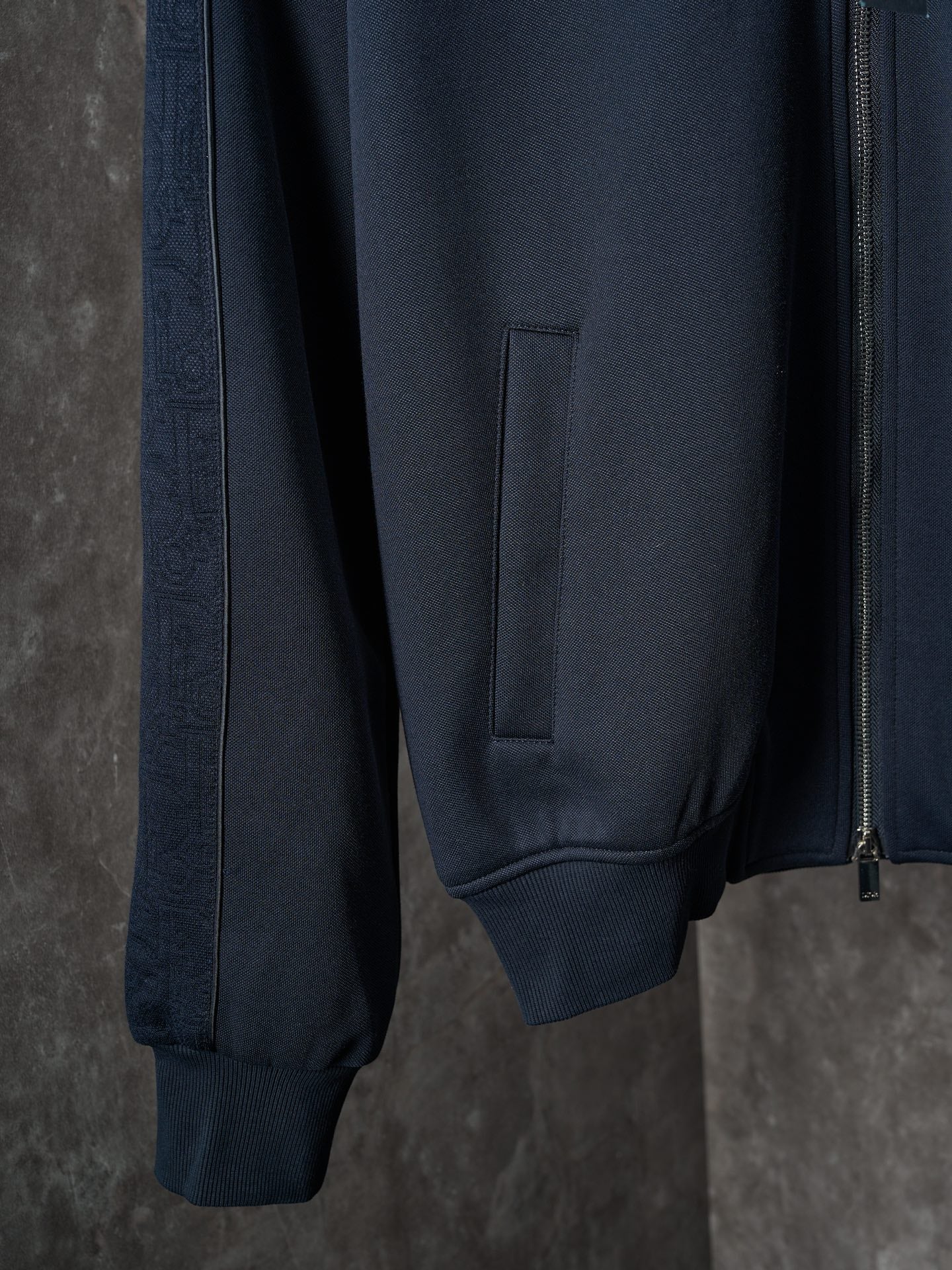 Navy jacket side view with front pocket and ribbed cuffs
