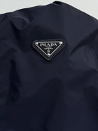 Prada triangular logo patch on dark navy jacket with silver trim