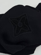 Louis Vuitton sweater sleeve close-up in dark knit with embossed monogram emblem
