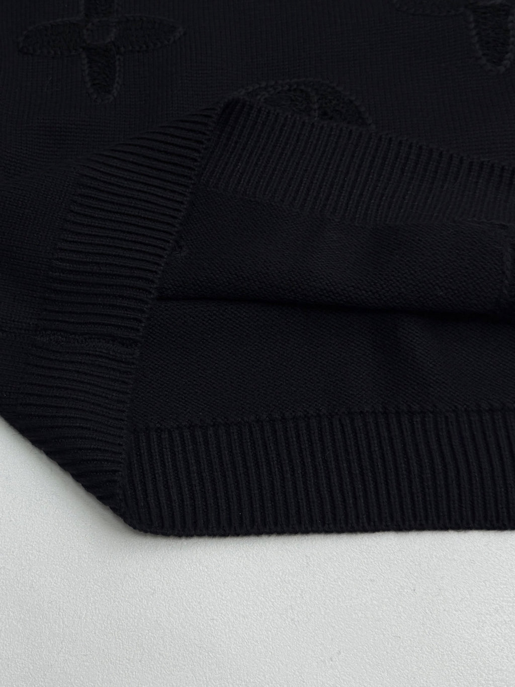 Louis Vuitton sweater knit texture detail in dark with raised monogram motifs