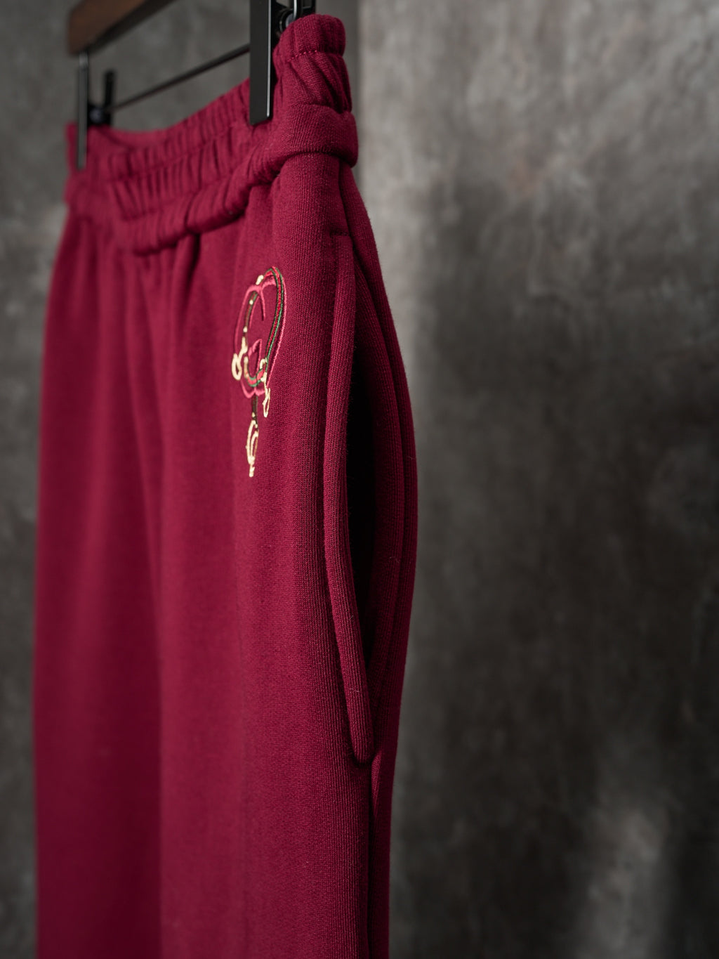 Maroon Gucci sweatpants with embroidered horsebit-style logo on the side