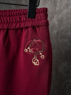 Maroon Gucci sweatpants with embroidered logo on hip beneath gathered waist