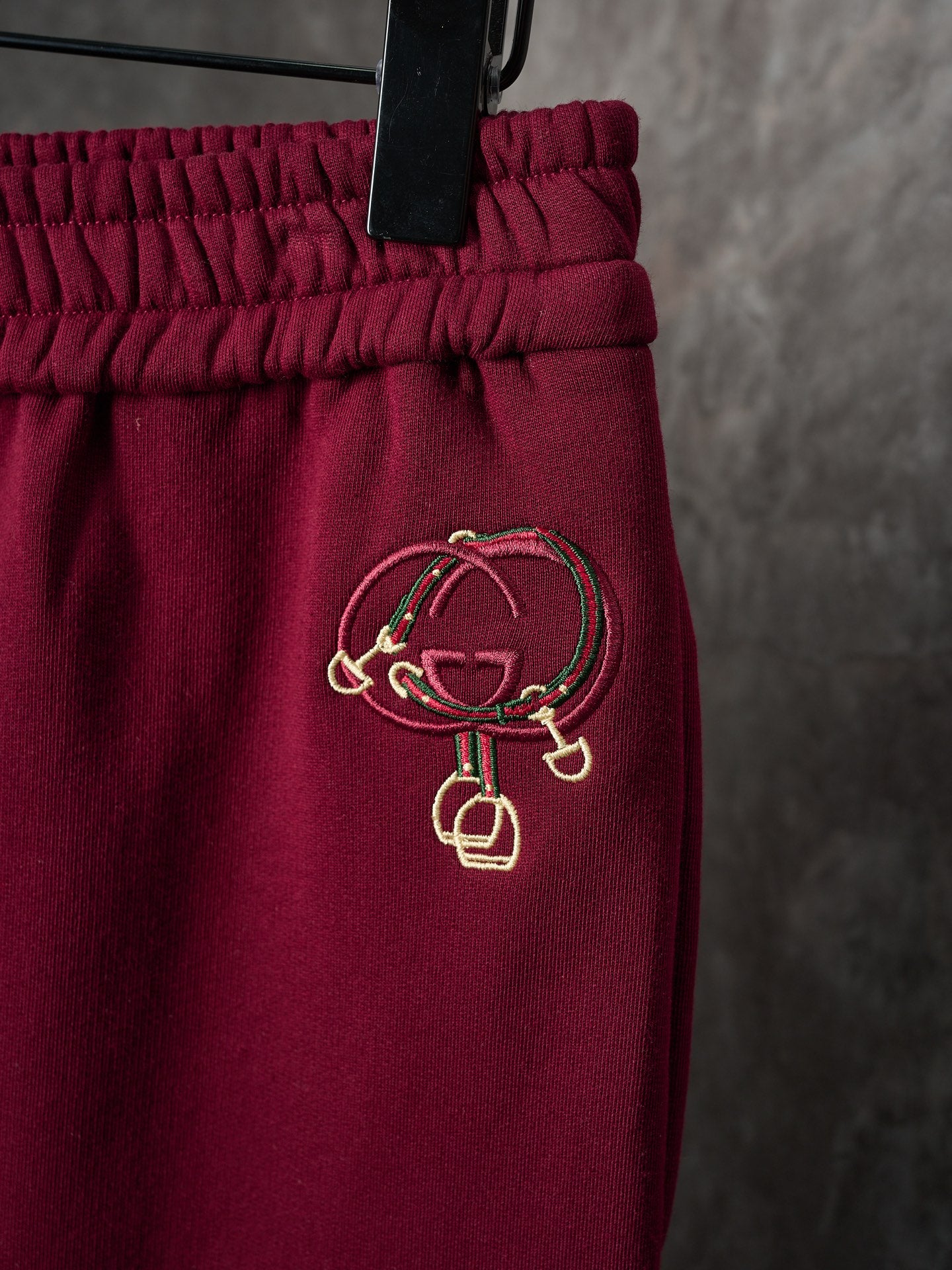 Maroon Gucci sweatpants with embroidered logo on hip beneath gathered waist