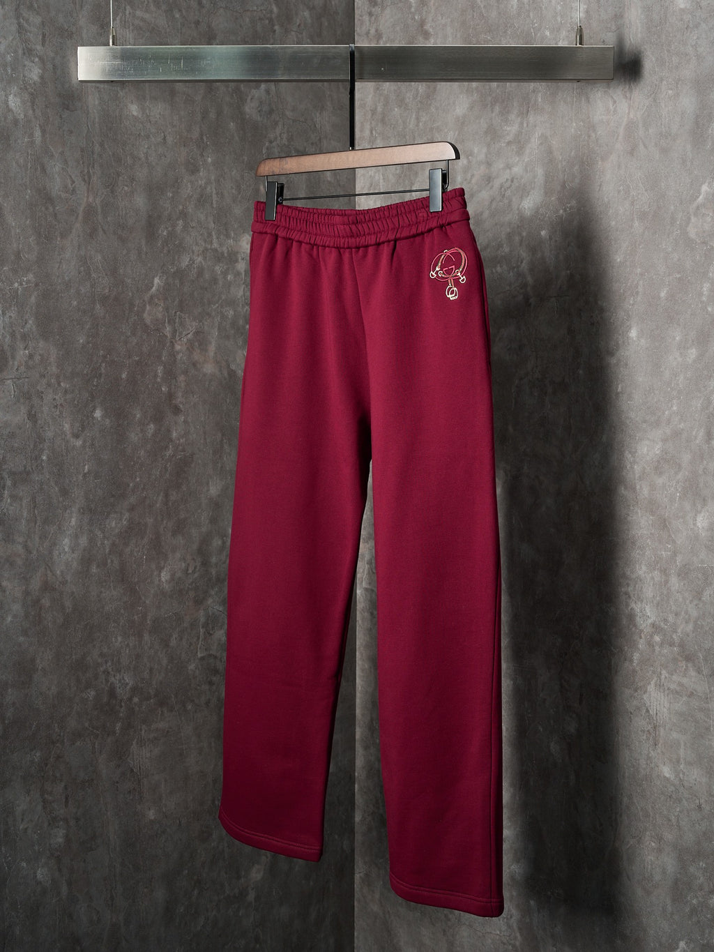 Maroon Gucci sweatpants with elastic waist and small embroidered logo on hip