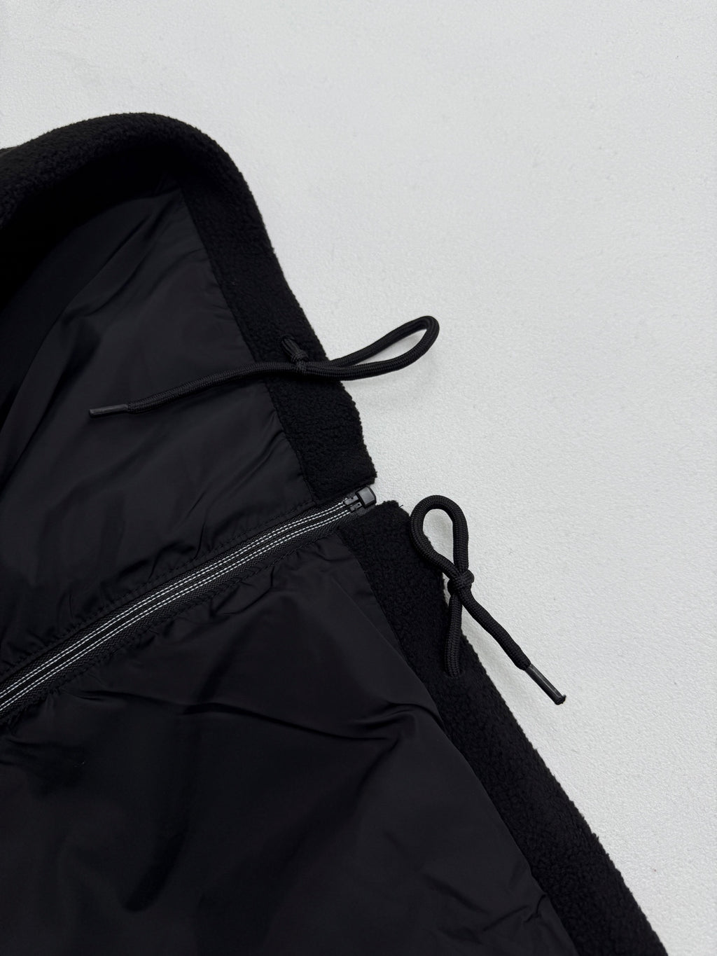 Black jacket with adjustable drawstring near zipper