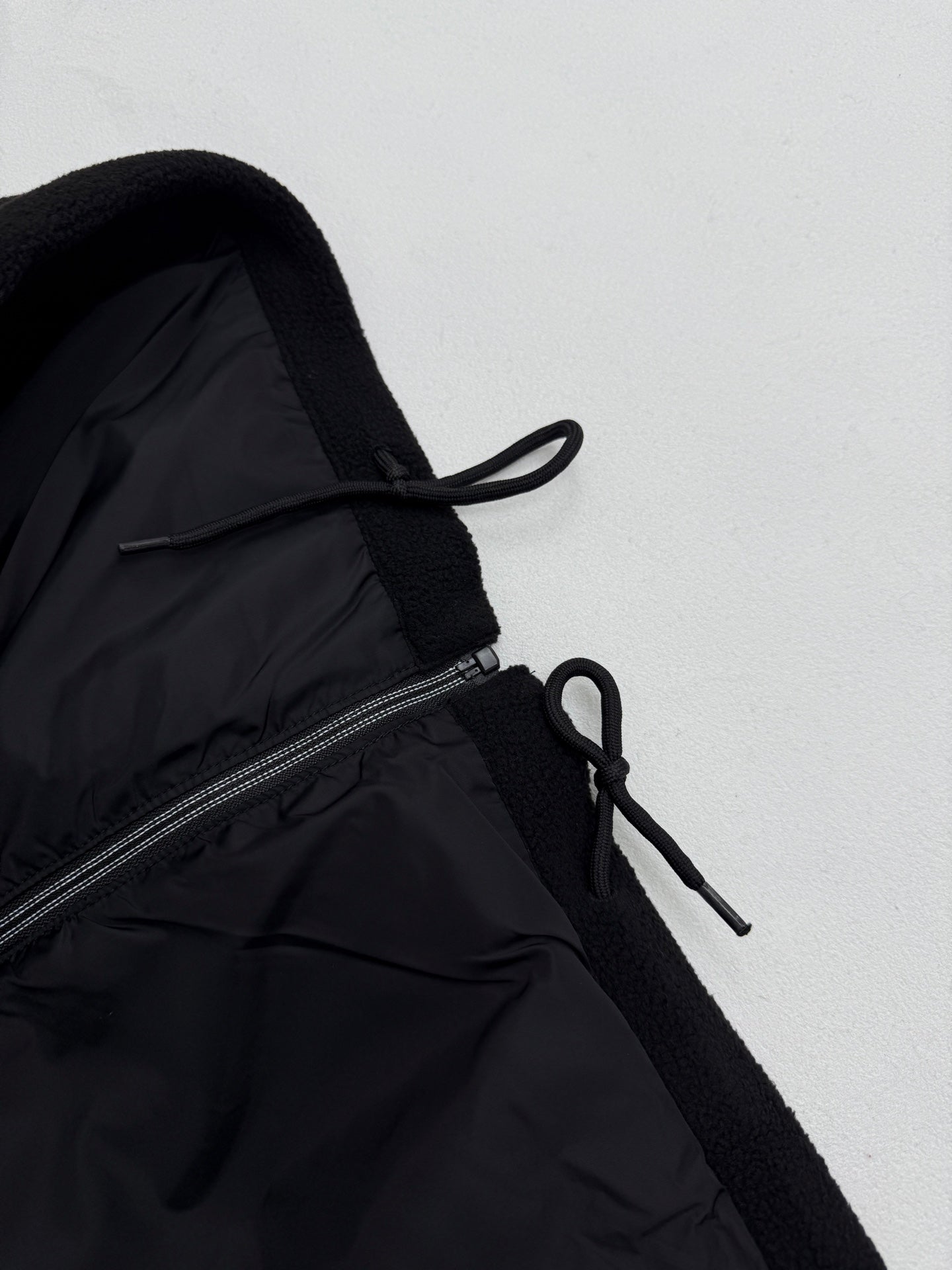 Black jacket with adjustable drawstring near zipper