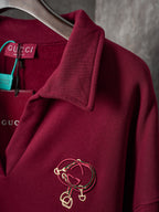 Burgundy long-sleeve polo sweatshirt with gold-tone crest embroidery on sleeve