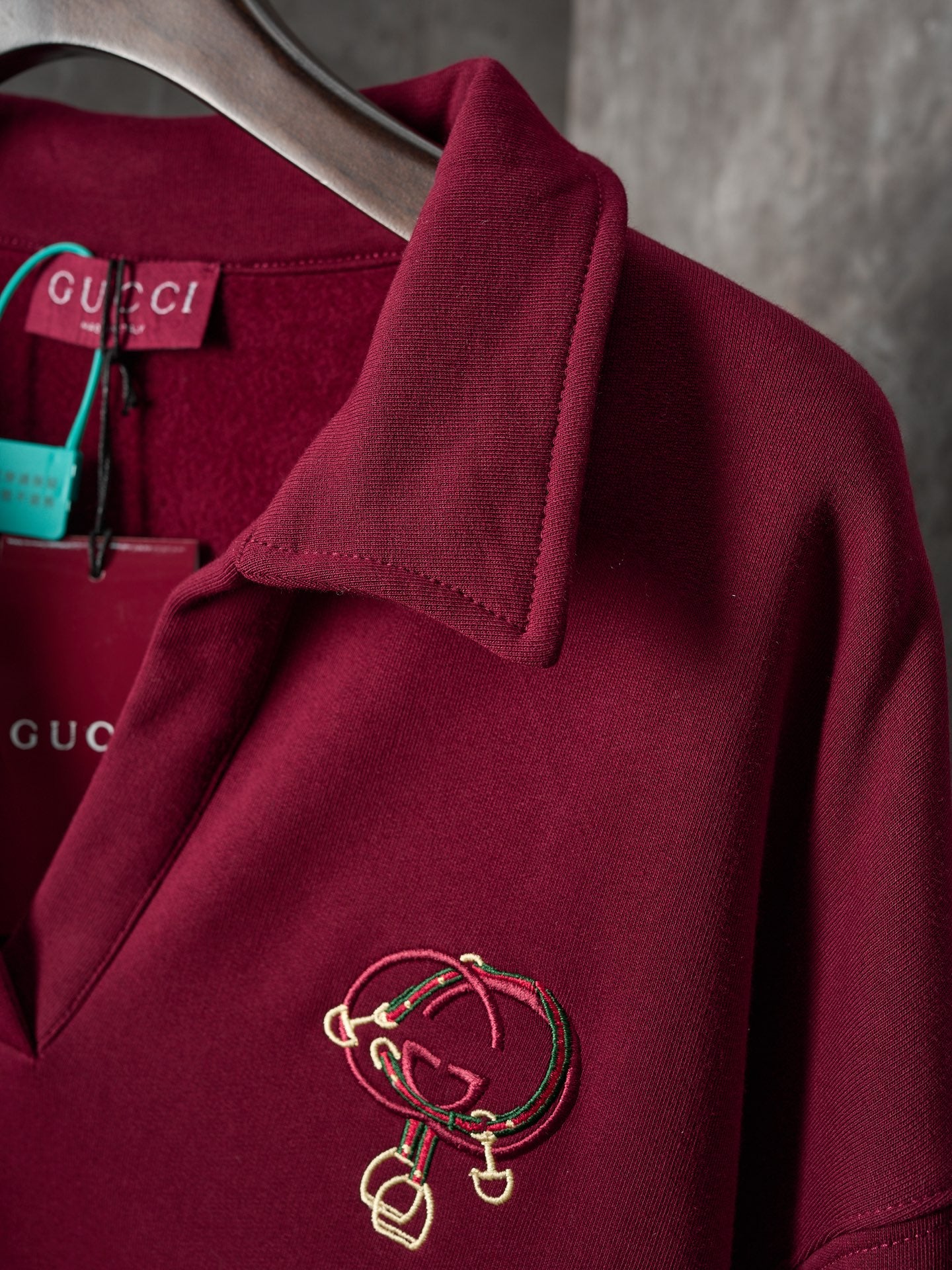 Burgundy long-sleeve polo sweatshirt with gold-tone crest embroidery on sleeve