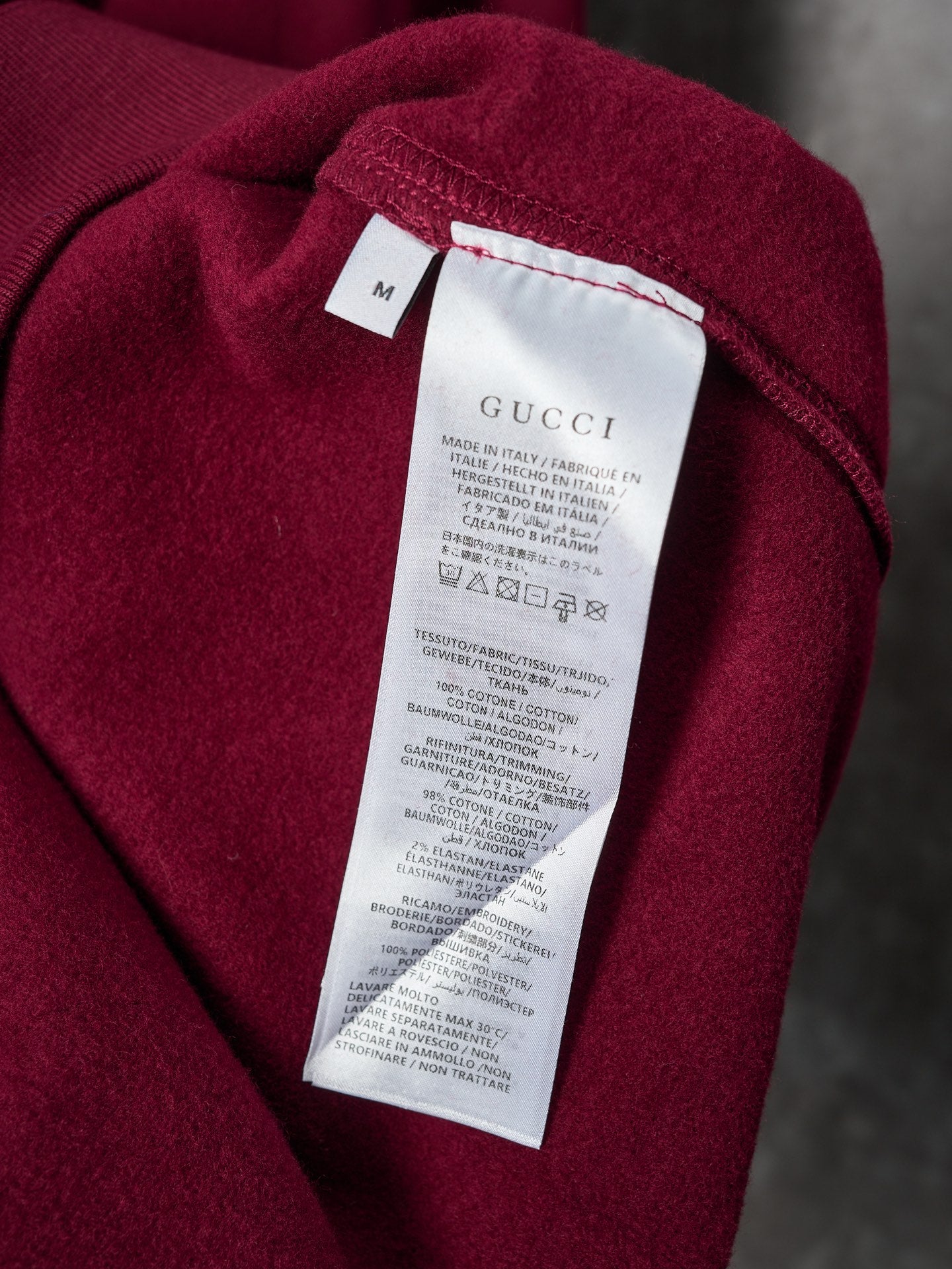 Burgundy polo sweatshirt with white Gucci care label near neckline