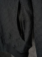 Long jacket sleeve close-up in dark allover GG pattern with diagonal zipper